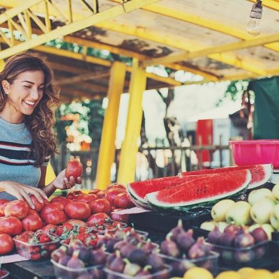 Smiling woman choosing fruits and vegetables on the farmer's market.